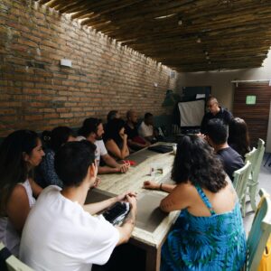 A diverse group of adults attentively participates in an indoor educational workshop.