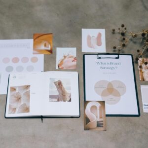 A flat lay of branding elements with color palettes and strategic planning documents on a concrete surface.
